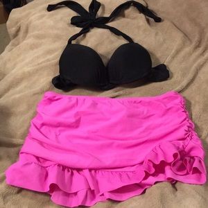 Women’s black bikini top and pink swim skirt.